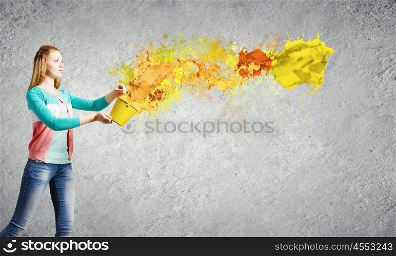 Painting concept. Young girl holding bucket with colorful splashes