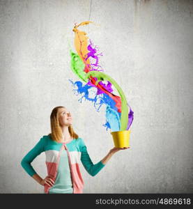 Painting concept. Young girl holding bucket with colorful splashes