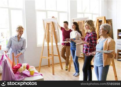 painting, education and people concept - group of artists or students and teacher with still life and easels at art school studio. students and teacher with still life at art school