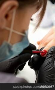Painting nails of a woman. Hands of Manicurist in black gloves applying red nail polish on female Nails in a beauty salon. Painting nails of a woman. Hands of Manicurist in black gloves applying red nail polish on female Nails in a beauty salon.