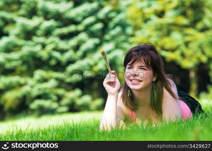 Painting the world. Smiling girl on grass with a paintbrush