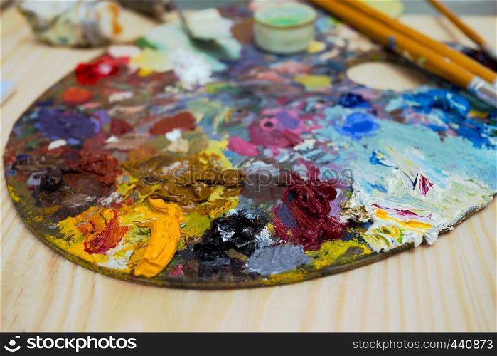 paints, brushes, palette lying on a wooden table