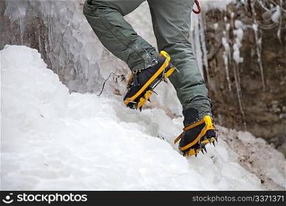 Pair of alpinist boots in crampons on ice
