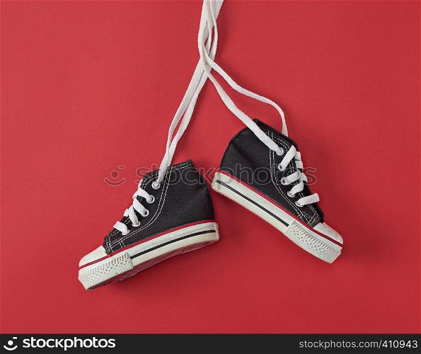 pair of black old textile sneakers on a red background