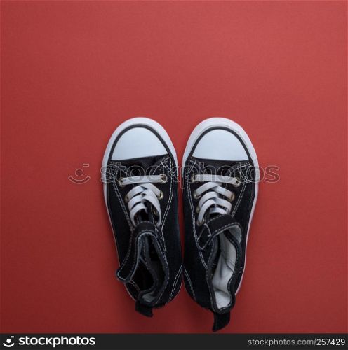 pair of black old textile sneakers on a red background, top view