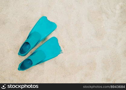 Pair of blue flippers on sand background, top view. Swimming equipment - fins on shore. Summer vacation, fun, exploration of marine world concept. Copy space. High quality photo. Pair of blue flippers on sand background, top view. Swimming equipment 