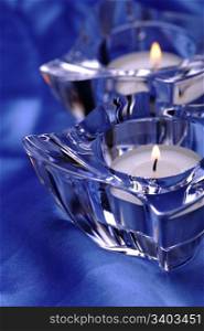 Pair of candles in a glass candlesticks, blue silk background