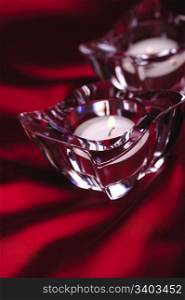 Pair of candles in a glass candlesticks, red silk background