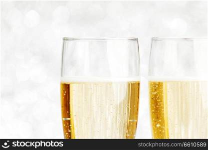 Pair of ch&agne flutes on shiny glitter background