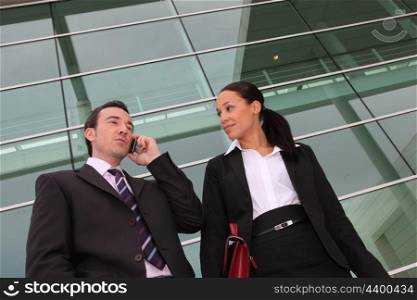 Pair of execs using a cellphone outside an office building