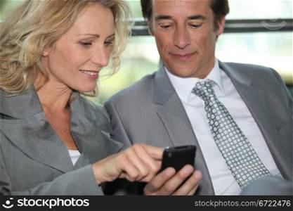 Pair of executives looking at something on a cellphone