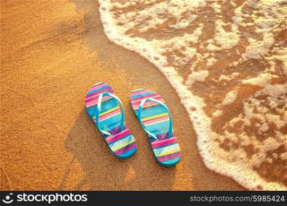 pair of flip-flops on a sandy beach at sunset, holiday and vacation concept