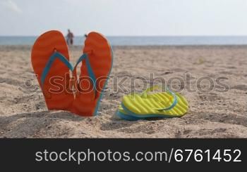 Pair of flip flops on a sandy beach in summer close-up