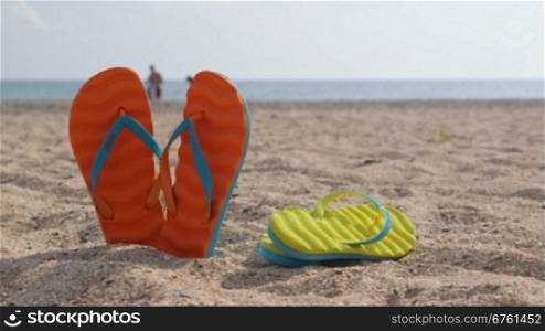Pair of flip flops on a sandy beach in summer close-up