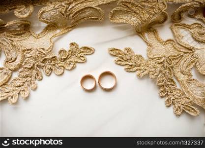 Pair of golden wedding rings over veil with lace. wedding accessories. selective focus.. Pair of golden wedding rings over veil with lace. wedding accessories. selective focus