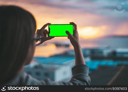 Pair of hands holding a smartphone on a green screen