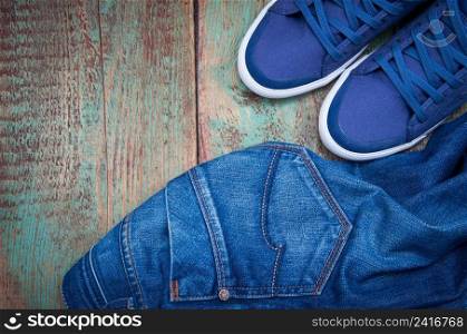 Pair of jeans thrown on floor with a pair of sneakers