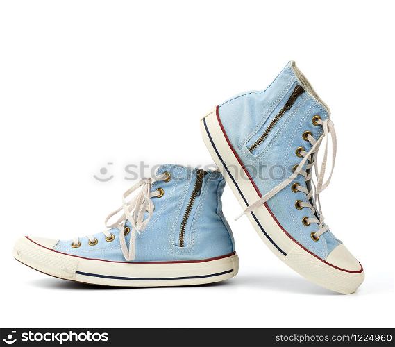 pair of light blue worn textile sneakers with laces and zippers on a white background, side view of shoes