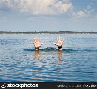 pair of masculine hands sticks out of the sea water on a summer day, gesture of a man who sinks