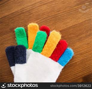 Pair of multicolor children&rsquo;s gloves on wooden table