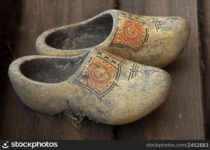 Pair of old dirty traditional Dutch wooden shoes on the floor 