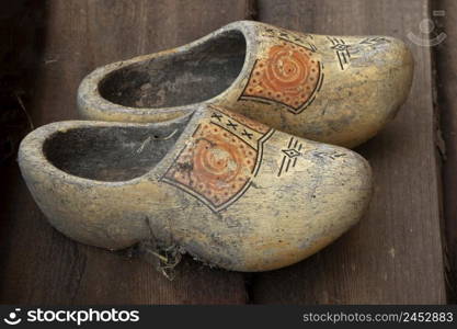 Pair of old dirty traditional Dutch wooden shoes on the floor 