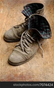 Pair of old leather shoes, worn-out and dusty, on wooden background. Pair of old shoes