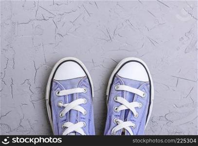 pair of old worn purple  sneakers with white laces on a gray  background, top view