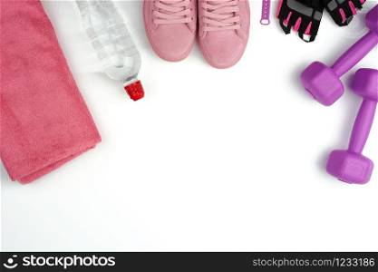 pair of pink leather sneakers, plastic dumbbells and gloves for sports on a white background, sports backdrop, top view, copy space