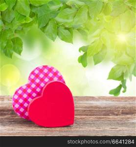 pair of red and  pink  hearts laying together on table in green garden. two red and  pink  hearts
