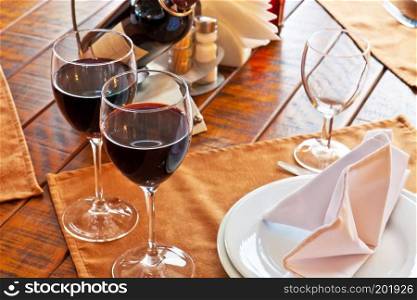 Pair of red wine goblets on served restaurant table. Selective focus effect
