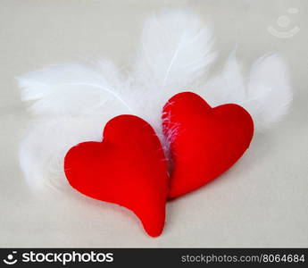 Pair of scarlet fluffy hearts among fluffy white feathers