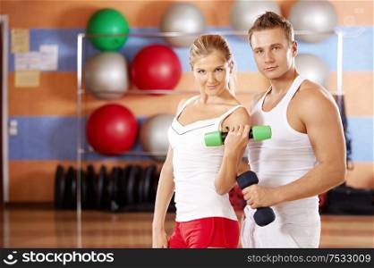Pair of sportsmen with dumbbells in hands in sports club