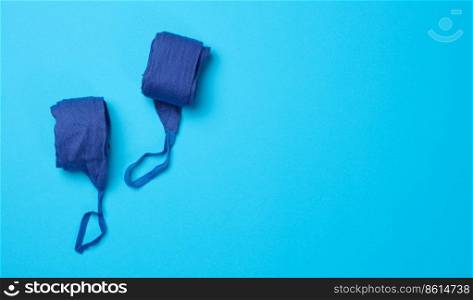 Pair of textile blue bandages for winding hands to athletes before sports training on a blue background, top view