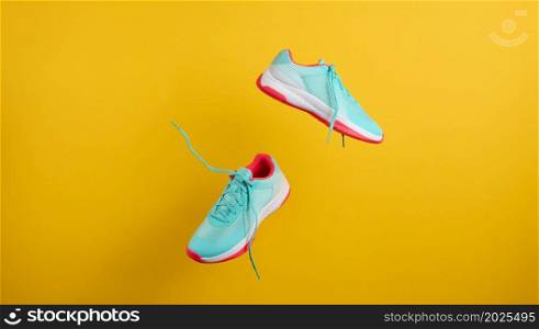 pair of textile blue sneakers with laces levitate on a yellow background. Shoes for sports, jogging