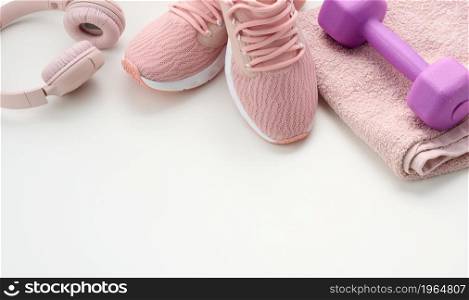 pair of textile purple sports sneakers, wireless headphones, a towel on a white background. Sportswear
