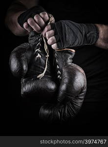 pair of very old boxing sports gloves in men&rsquo;s hands rewound with a black bandage