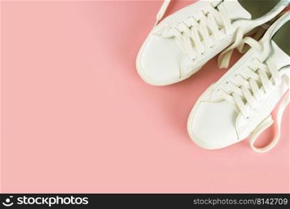 Pair of white sneakers on pink background. Unisex shoes, stylish white sneakers. Top view, flat lay, mockup with copy space for text. White sneakers on pink background