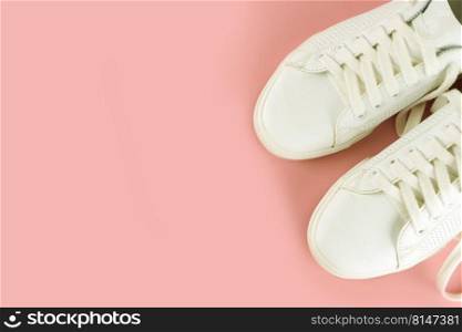 Pair of white sneakers on pink background. Unisex shoes, stylish white sneakers. Top view, flat lay, mockup with copy space for text. White sneakers on pink background