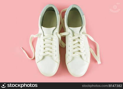 Pair of white sneakers on pink background. Unisex shoes, stylish white sneakers. Top view, flat lay, mockup with copy space for text. White sneakers on pink background