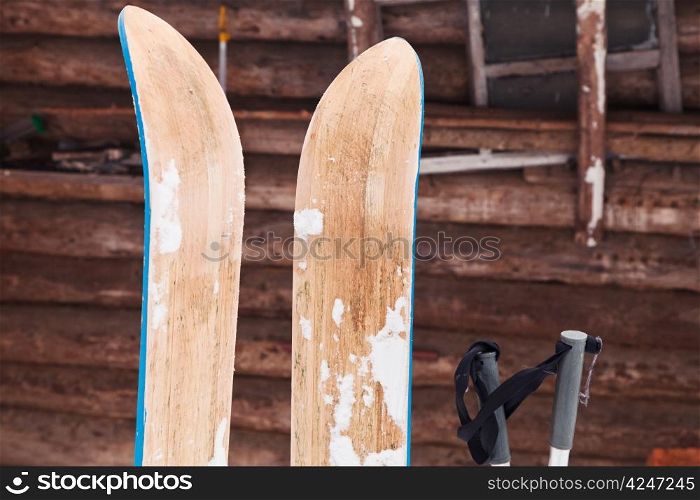 pair of wide wooden hunting skis and log house wall in winter day