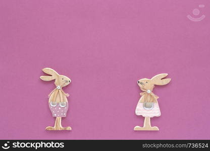 pair of wooden easter bunnies on purple paper background. Concept Easter or Valentine's day Copy space Template for lettering, text or your design Creative Top View.. pair of wooden easter bunnies on purple paper background. Concept Easter or Valentine's day Copy space Template for lettering, text or your design Creative Top View