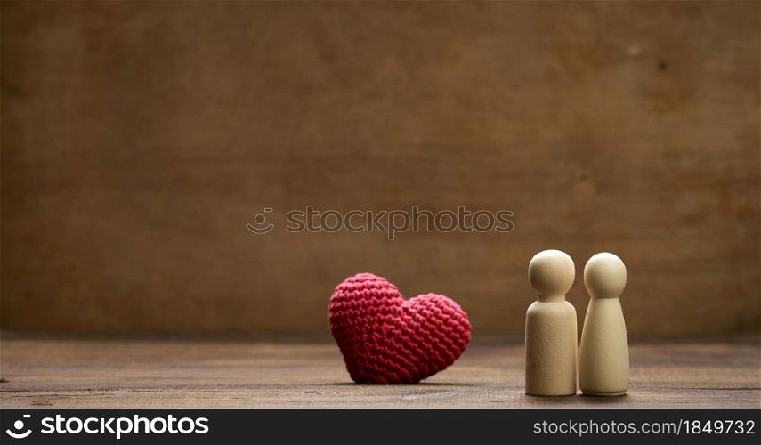 pair of wooden men of the bride and groom, red heart, brown background, concept of love and relationships. Copys pace
