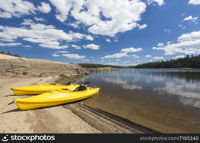 Pair of Yellow Kayaks on a Beautiful Mountain Lake Shore.