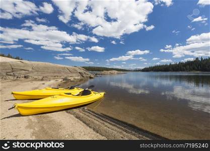 Pair of Yellow Kayaks on a Beautiful Mountain Lake Shore.