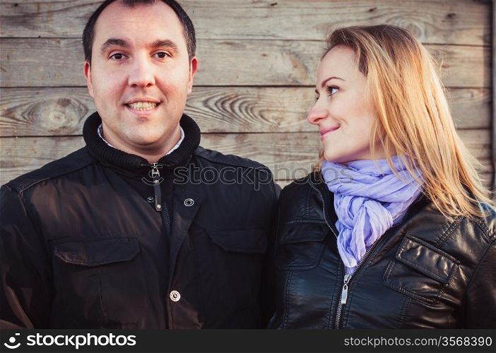 Pair of young people standing near wooden wall