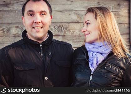 Pair of young people standing near wooden wall