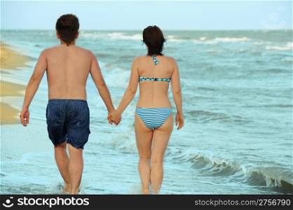 Pair on seacoast. The enamoured guy and the girl walking on coast