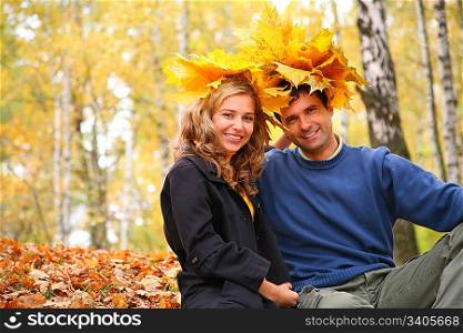 Pair with maple leaves on head in autumn wood