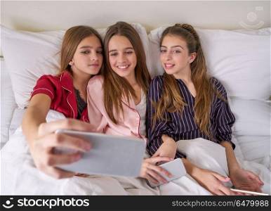 Pajama party best friend girls selfie at bed. Pajama party best friend girls selfie at bed with tablet and smartphone